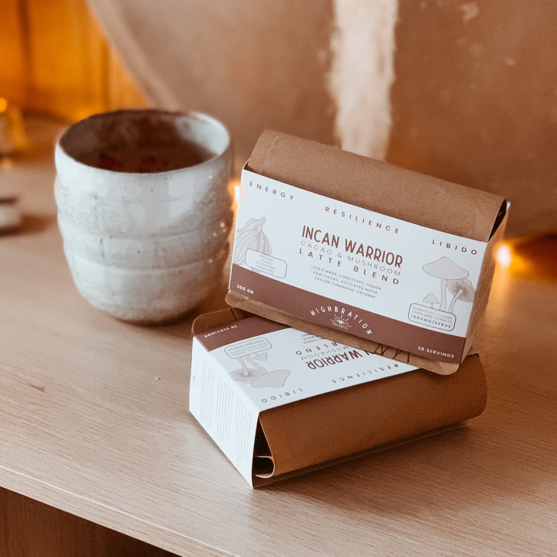 Two coffee packages labeled 'Incan Warrior' on a wooden surface with a ceramic cup in the background.